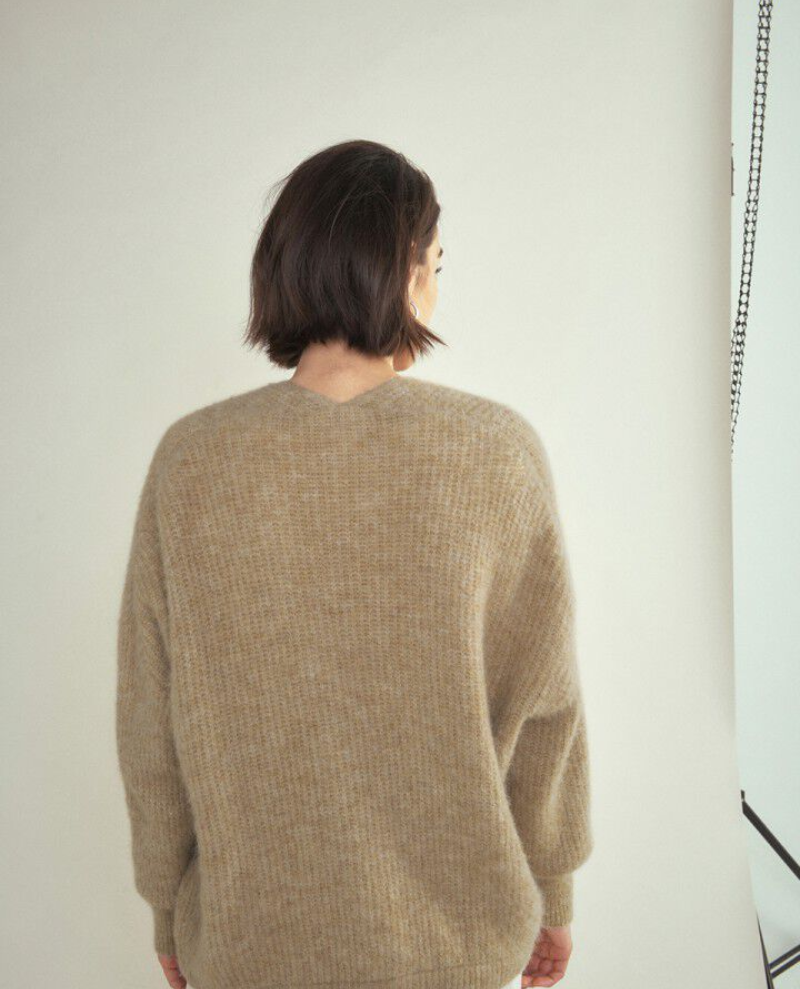 Model wearing beige cardigan with back to camera